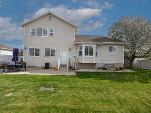 Back of property featuring entry steps, a fenced backyard, a lawn, and a patio area