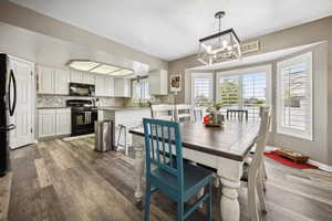 Dining space with a notable chandelier, baseboards, and wood finished floors