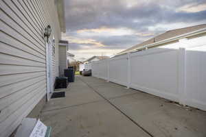 Patio terrace at dusk with cooling unit and a fenced backyard