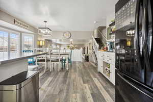 Kitchen with a chandelier, white cabinetry, freestanding refrigerator, open shelves, and dark wood finished floors