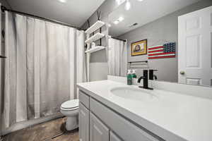 Full bathroom featuring toilet, wood finished floors, vanity, and visible vents