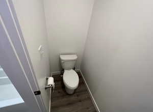 Bathroom with baseboards, toilet, and wood finished floors