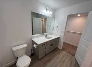 Bathroom featuring vanity, baseboards, toilet, and wood finished floors