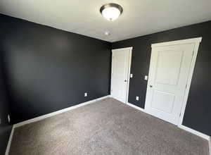 Unfurnished room featuring a textured ceiling, baseboards, and carpet floors
