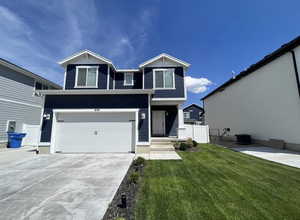 Traditional home with central AC unit, an attached garage, fence, concrete driveway, and a front lawn