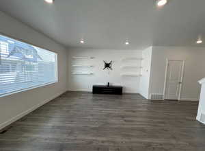 Unfurnished living room featuring dark wood-style flooring, visible vents, and recessed lighting