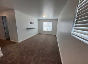 Empty room with baseboards, carpet, and a textured ceiling