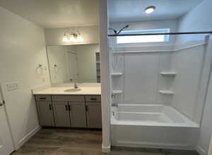 Full bathroom featuring a textured ceiling, vanity, wood finished floors, washtub / shower combination, and baseboards