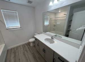 Bathroom featuring vanity, visible vents, toilet, wood finished floors, and baseboards