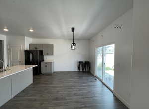 Kitchen featuring baseboards, light countertops, freestanding refrigerator, dark wood-style floors, and gray cabinets
