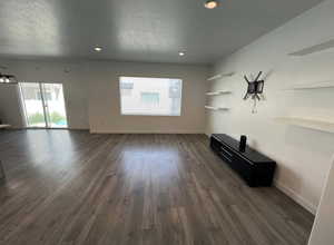 Unfurnished living room with plenty of natural light, dark wood-style floors, and baseboards