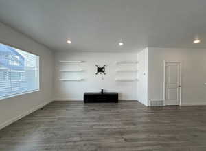 Unfurnished living room featuring baseboards, dark wood finished floors, visible vents, and recessed lighting