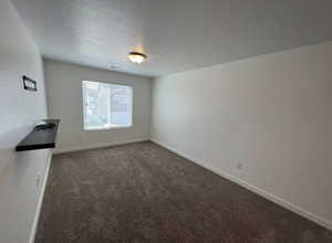 Unfurnished living room with carpet flooring, visible vents, a textured ceiling, and baseboards