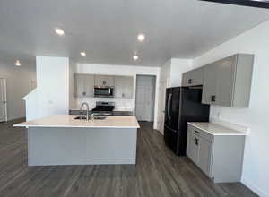 Kitchen with dark wood-type flooring, gray cabinets, a sink, stainless steel appliances, and baseboards