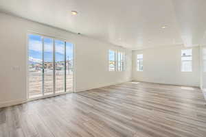 Empty room featuring light wood-style flooring, baseboards, visible vents, and recessed lighting