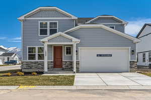 View of front of home with stone siding, a garage, and concrete driveway