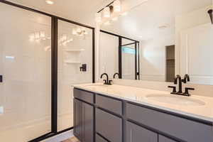 Full bath with double vanity, visible vents, a sink, and a stall shower