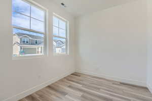 Spare room with light wood finished floors, baseboards, and visible vents