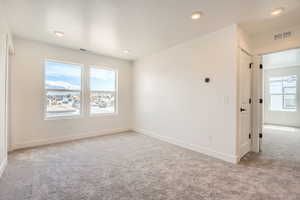 Carpeted spare room featuring baseboards, visible vents, and recessed lighting