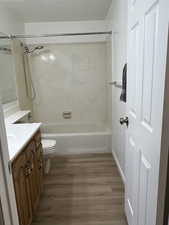 Bathroom featuring tub / shower combination, vanity, toilet, and wood finished floors