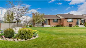 View of front of house featuring a front yard, brick siding, and fence