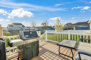 Wooden deck featuring a residential view, fence, and a lawn