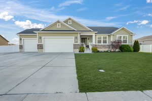 Craftsman-style home with concrete driveway, stone siding, an attached garage, a front yard, and fence