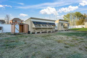 Rear view of property featuring an outdoor structure, fence, a lawn, and a shed