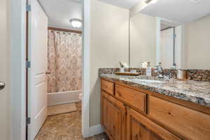 Bathroom with visible vents, toilet, shower / tub combo with curtain, stone finish floor, and vanity
