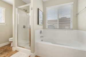 Full bath featuring a shower stall, a garden tub, and toilet