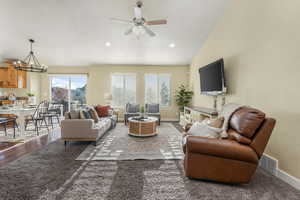 Living room featuring baseboards, vaulted ceiling, recessed lighting, visible vents, and ceiling fan with notable chandelier