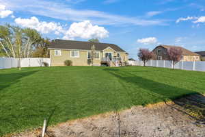 Rear view of house featuring a fenced backyard, a wooden deck, and a lawn