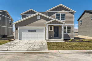 Traditional home with an attached garage, board and batten siding, and concrete driveway