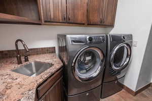 Clothes washing area with washer and dryer, a sink, and cabinet space
