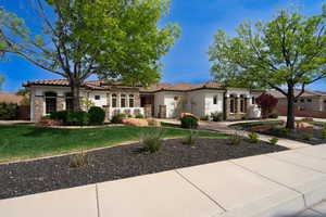 Mediterranean / spanish house featuring concrete driveway, stucco siding, stone siding, a front lawn, and a tiled roof
