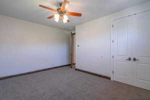 Unfurnished bedroom with a closet, carpet flooring, baseboards, and a ceiling fan