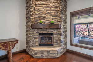 Interior details featuring a stone fireplace, baseboards, and wood finished floors