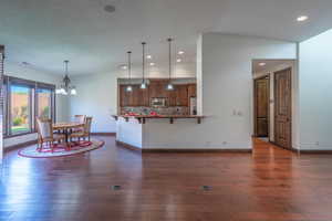 Kitchen with dark wood-style flooring, an inviting chandelier, a kitchen bar, and stainless steel appliances
