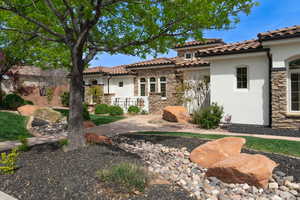 Rear view of property with stucco siding, stone siding, and a tile roof