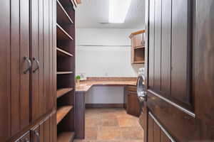 Home office with built in study area, visible vents, a textured ceiling, and baseboards