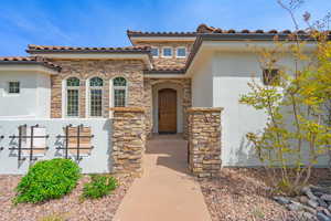 View of front of home with stucco siding, stone siding, and a tile roof