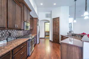 Kitchen featuring tasteful backsplash, arched walkways, visible vents, appliances with stainless steel finishes, and a sink
