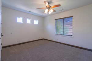 Carpeted empty room with ceiling fan, baseboards, and visible vents