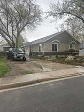 View of front of house with stone siding, driveway, and stucco siding