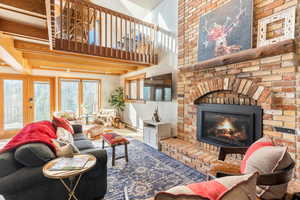 Living area with a fireplace, baseboards, and a towering ceiling