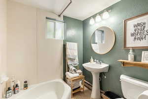 Bathroom with toilet, a baseboard radiator, and a textured wall