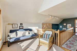Sitting room with track lighting, vaulted ceiling, carpet floors, an upstairs landing, and baseboards