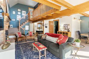 Living area featuring stairway, a large fireplace, lofted ceiling, and carpet floors