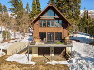 Snow covered house featuring a garage and stairs