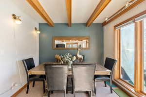 Dining area with beam ceiling, baseboards, and carpet